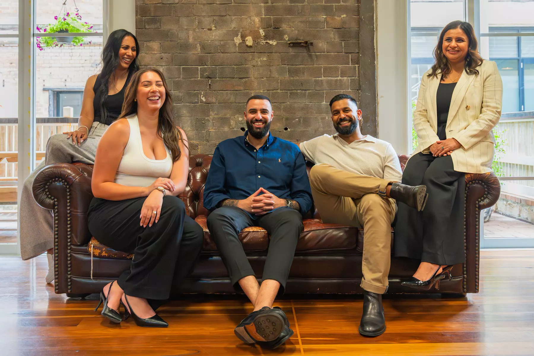 The InvestorMate team together on a leather sofa in the office